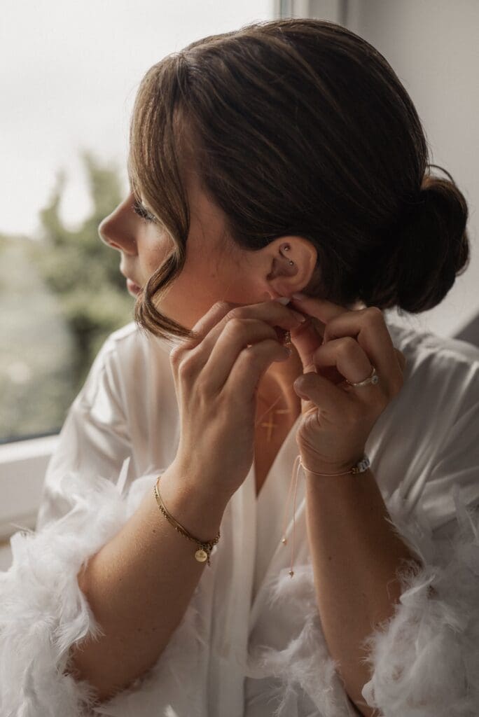 Braut zieht sich Ohrringe an beim Getting Ready für eine Hochzeit in Aachen