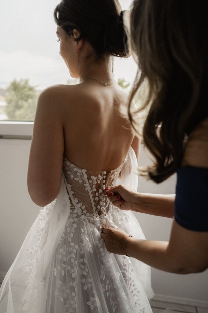 Detailbild wie Mama ihrer Tochter das Kleid anzieht beim Getting Ready der Hochzeit in Aachen